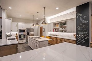 A modern kitchen with white cabinetry, stainless steel appliances, and pendant lighting. - The Alpine Vista | Pets | Couples | Golf | Nakoma (Portola)