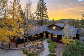 A modern house with a stone facade, a covered porch, and a well-maintained garden with autumn foliage. - The Alpine Vista | Pets | Couples | Golf | Nakoma (Portola)