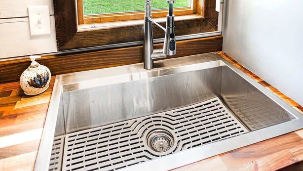 A kitchen with a stainless steel sink, a window with a view of a green landscape, and wooden cabinetry. - Equestrian Escape Sum (Blue Ridge)