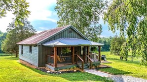 A rustic cabin with a metal roof, wooden porch, and a small front yard. - Equestrian Escape Sum (Blue Ridge)