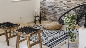 A room with a patterned rug, a woven pouf, a wooden stool, and a black chair. - Oasis apartment - City center by HD (Faro)