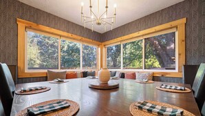 Un comedor con una gran mesa de madera, individuales tejidos y un jarrón central.