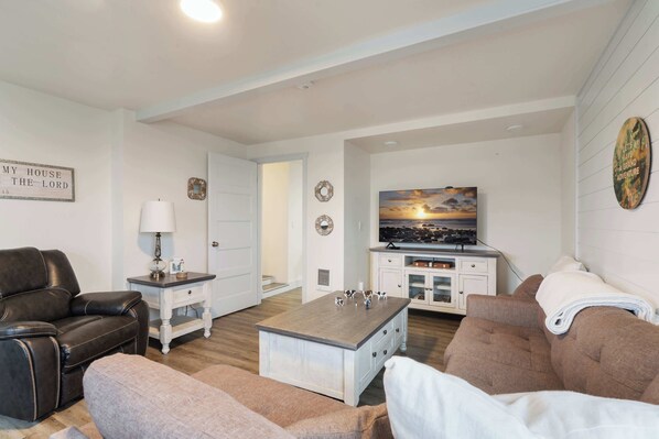 A living room with a leather sofa, a brown couch, a coffee table, and a television on a white cabinet.