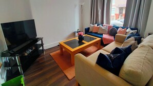 Un salon équipé d’un téléviseur à écran plat, d’un canapé, d’une table basse et d’une horloge murale.