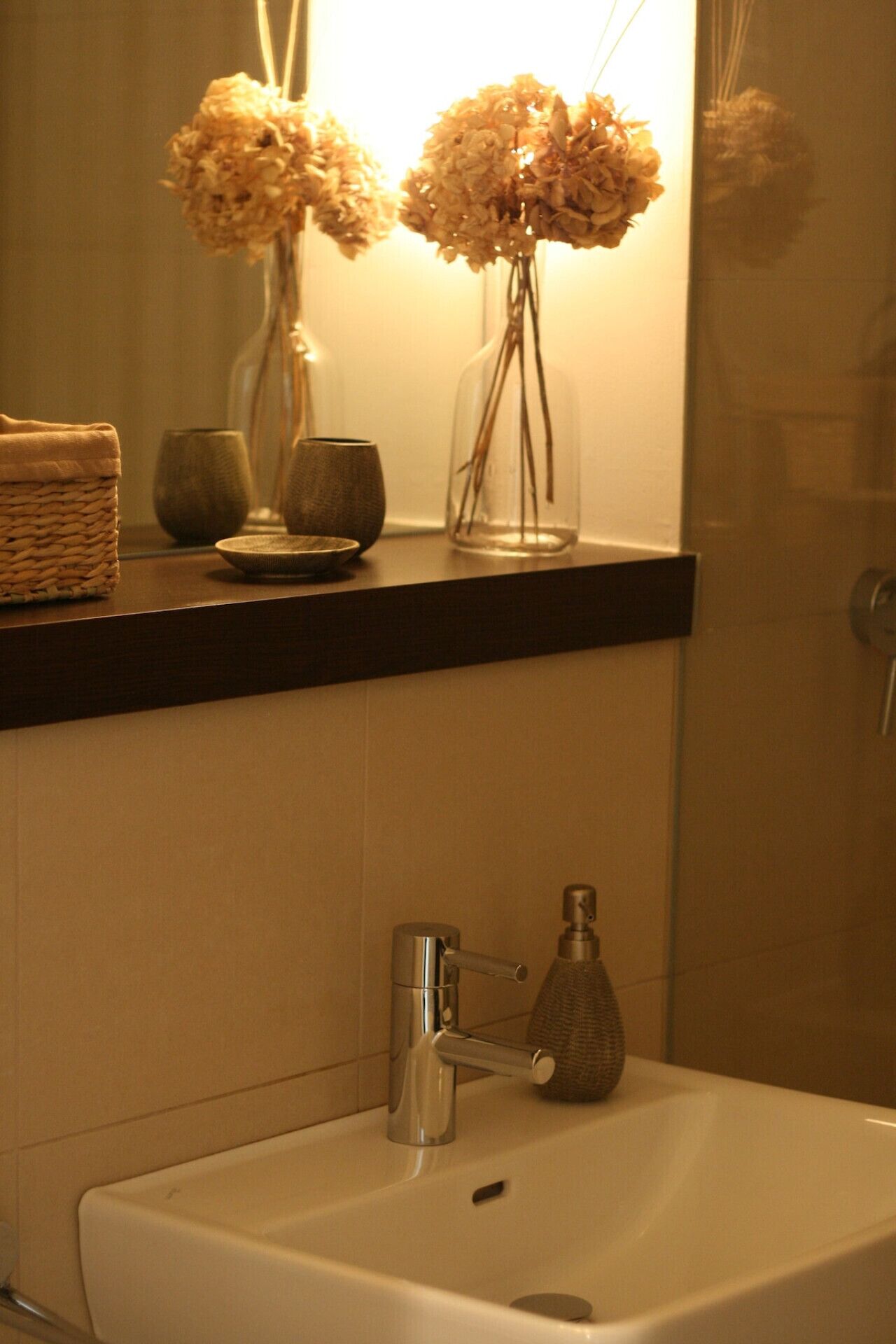 A bathroom with a sink, a mirror, and a shelf with decorative items.