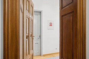Ein Flur mit Holztüren, darunter eine weiße Tür mit einem Rauchverbotsschild, und einem hellen Boden.