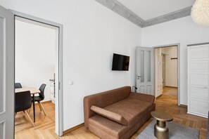 Ein modernes Wohnzimmer mit einer Couch, einem Fernseher und einem Essbereich mit Stühlen und einem Tisch.