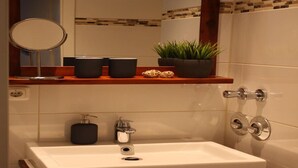 A bathroom with a white sink, a mirror, a towel rack, and a shelf with toiletries. - Apartment-Ensuite with Shower-Terrace near Bayerischer (Leipzig)