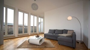 Un salon moderne avec un canapé gris, une table basse blanche et un lampadaire.