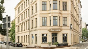A multi-story building with a classical architectural style, featuring a prominent entrance labeled "Restaurant" on the ground floor. - Apartment-Superior-Ensuite (Leipzig)