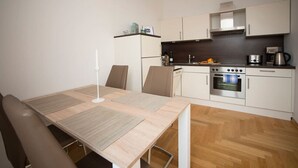A modern kitchen with white cabinets, a built-in oven, and a coffee maker. - Apartment-Superior-Ensuite (Leipzig)