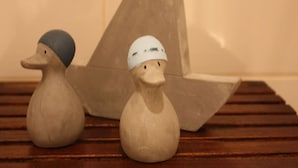 Two wooden duck figurines on a wooden surface with a large wooden sailboat in the background. - Apartment-Ensuite with Bath-City view (Leipzig)