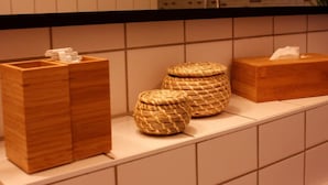 A bathroom with a wooden vanity, two woven baskets, and a tissue box. - Apartment-Ensuite with Bath-City view (Leipzig)