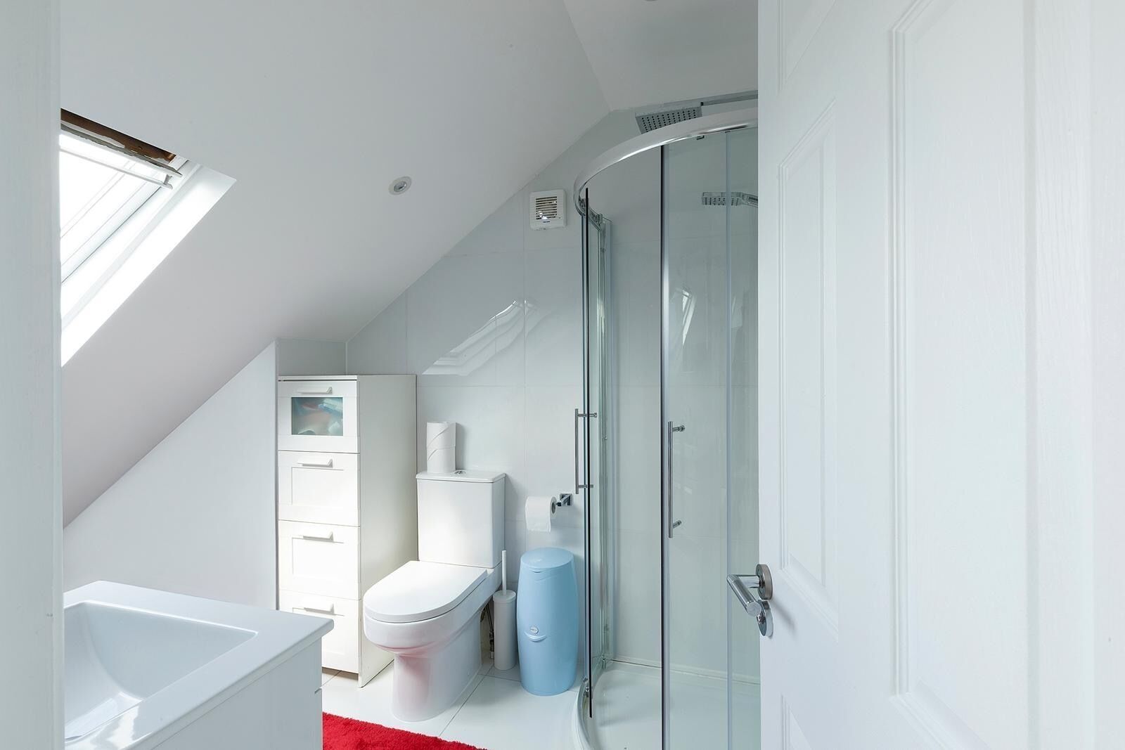 A modern bathroom with a shower, toilet, and sink.