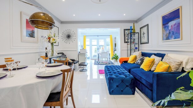 A modern living room with a blue sofa, dining table set, and a bright, well-lit space with a view to the outside. - Wavertree Hotel (London)
