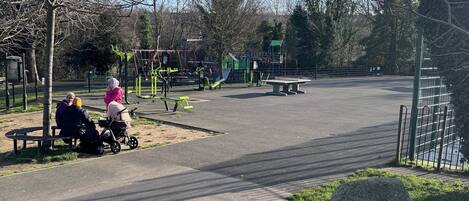A park with exercise equipment, benches, and a paved path.