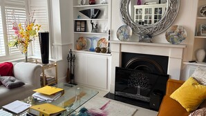 A living room with a glass coffee table, a fireplace, and a white mantelpiece. - Wavertree Hotel (London)