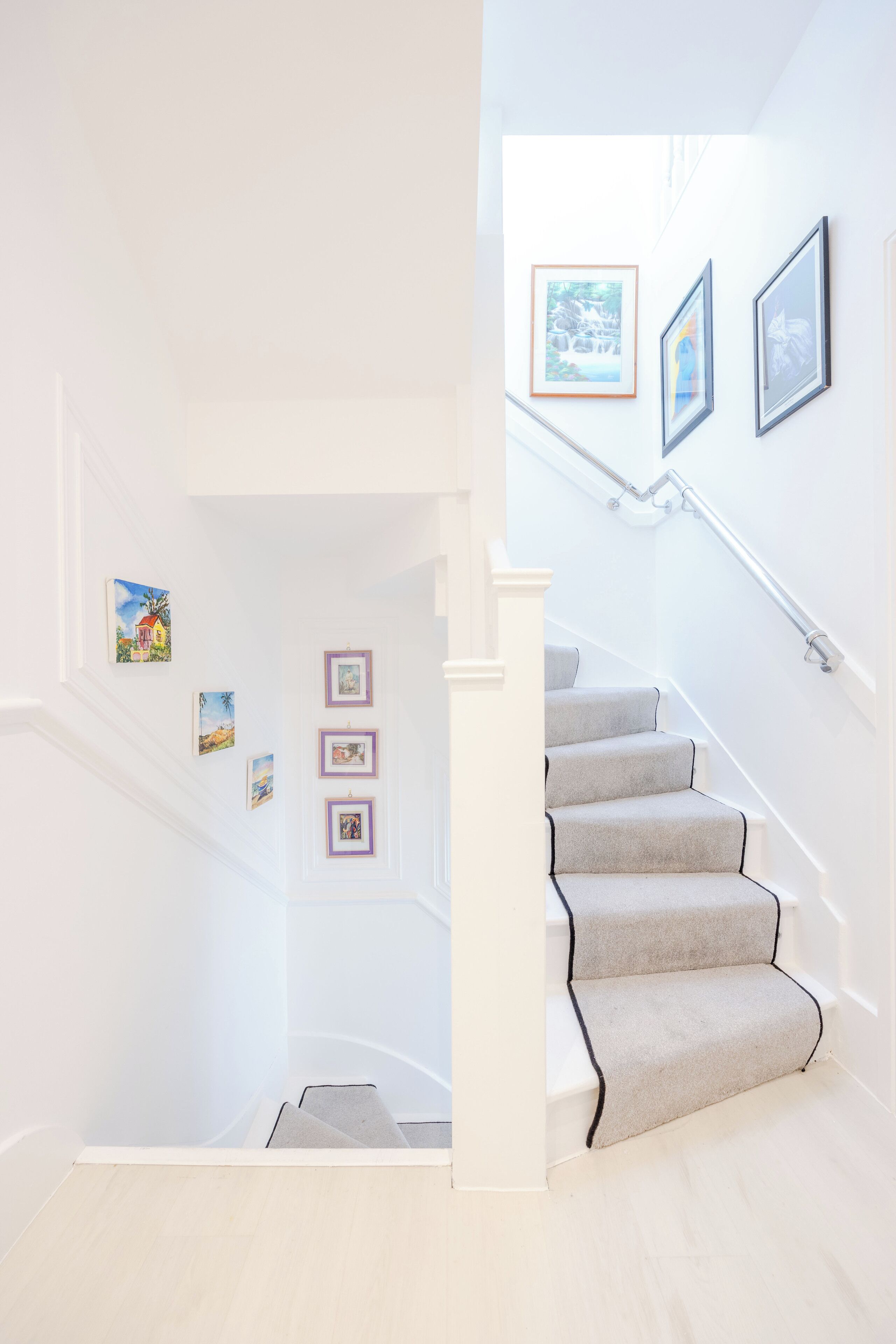A staircase with a handrail and a landing with framed pictures.