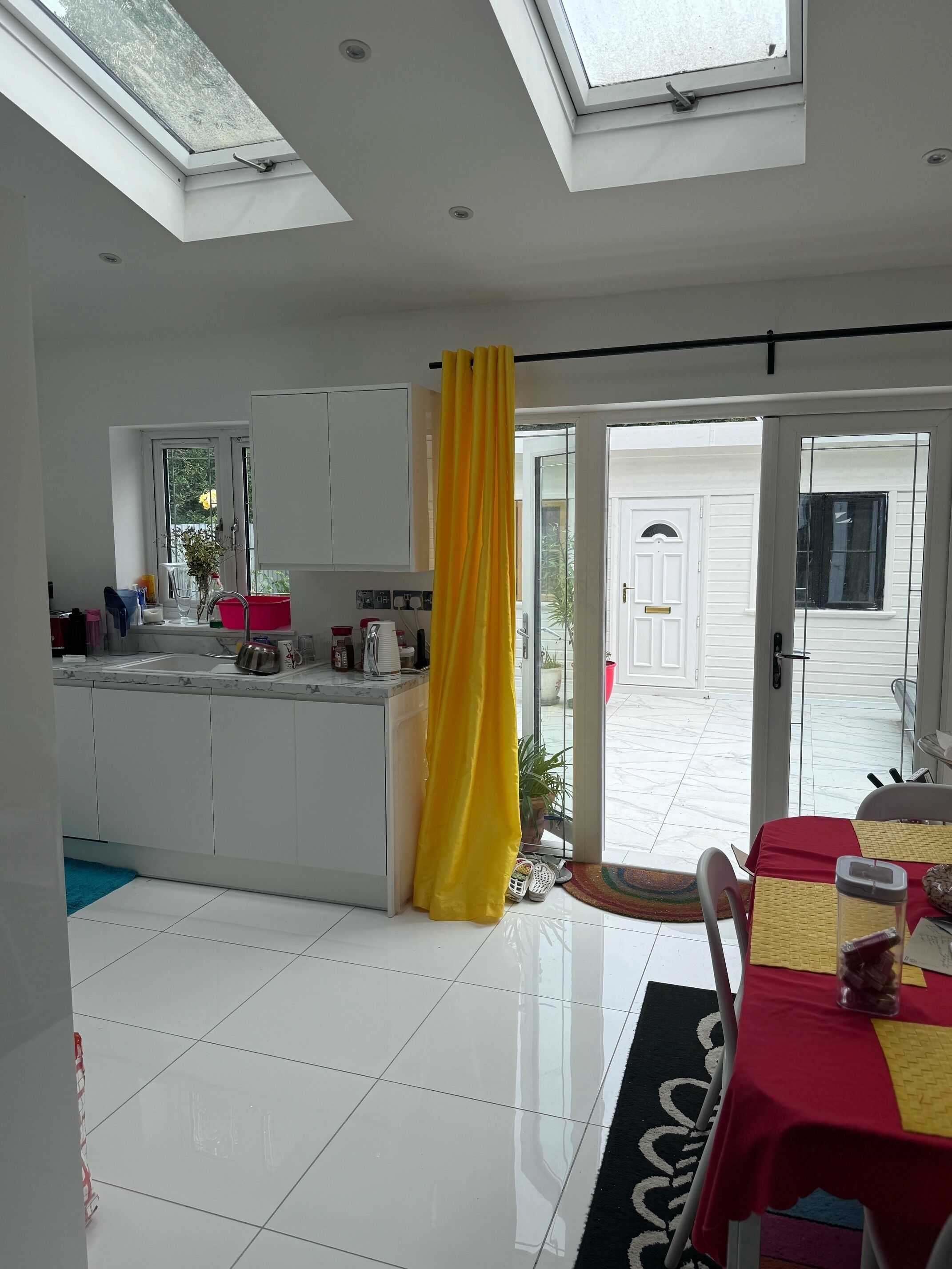 A modern kitchen with a central island, a dining area with a table, and a view of the outside.