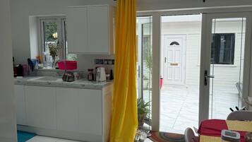A modern kitchen with a central island, a dining area with a table, and a view of the outside.