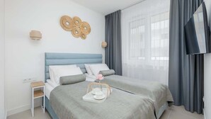Habitació d'hotel moderna amb llit, taula de nit i televisió penjada a la paret.