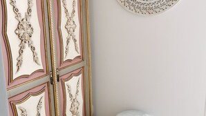 A room with a decorative cabinet, a round wall hanging, and a round ottoman.