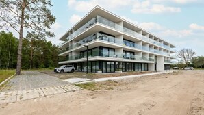 Un edificio de varios pisos con balcones, un camino pavimentado y una zona de estacionamiento.