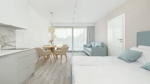 Una habitación de hotel moderna con cama, sofá, comedor y cocina.