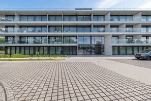 A multi-story building with a flat roof, large windows, and a paved entrance area. - Comfortable Studio in Mielno | Pool on the Roof and Parking (Mielno)