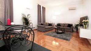 Ein modernes Wohnzimmer mit Essbereich, zwei Sofas, einem Couchtisch und einem Fernseher.