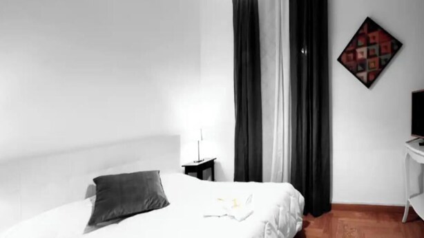 Ein Hotelzimmer mit einem Bett, einem Schreibtisch und einem an der Wand hängenden Kunstwerk.