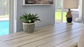 A room with a painting of a bird, a potted plant, and a lamp on a wooden table. - Tranquil Pool Home Minutes to Siesta Key (Sarasota)