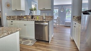 A modern kitchen with white cabinets, stainless steel appliances, and a granite countertop. - Tranquil Pool Home Minutes to Siesta Key (Sarasota)