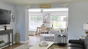 A modern living room with a dining area, a TV, and artwork on the walls. - Tranquil Pool Home Minutes to Siesta Key (Sarasota)