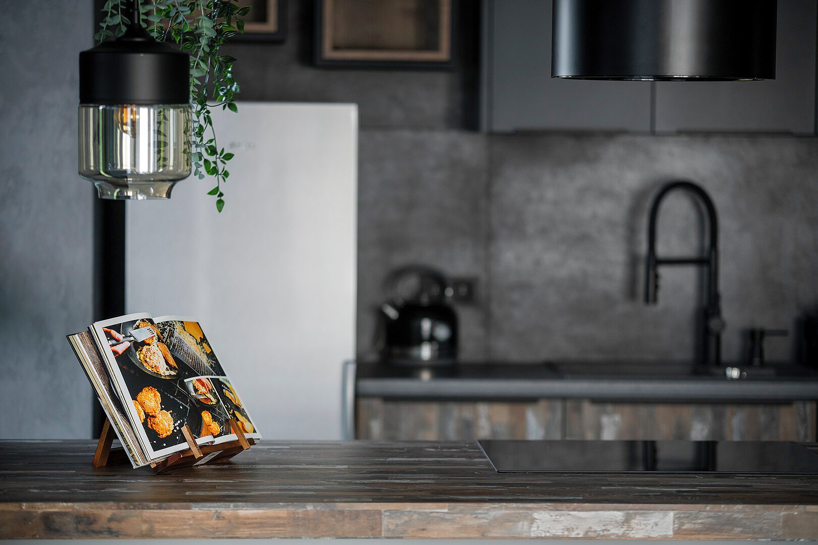 Una cocina de diseño moderno, con encimera de madera, lámpara colgante y campana extractora de acero inoxidable.