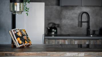Una cocina de diseño moderno, con encimera de madera, lámpara colgante y campana extractora de acero inoxidable.