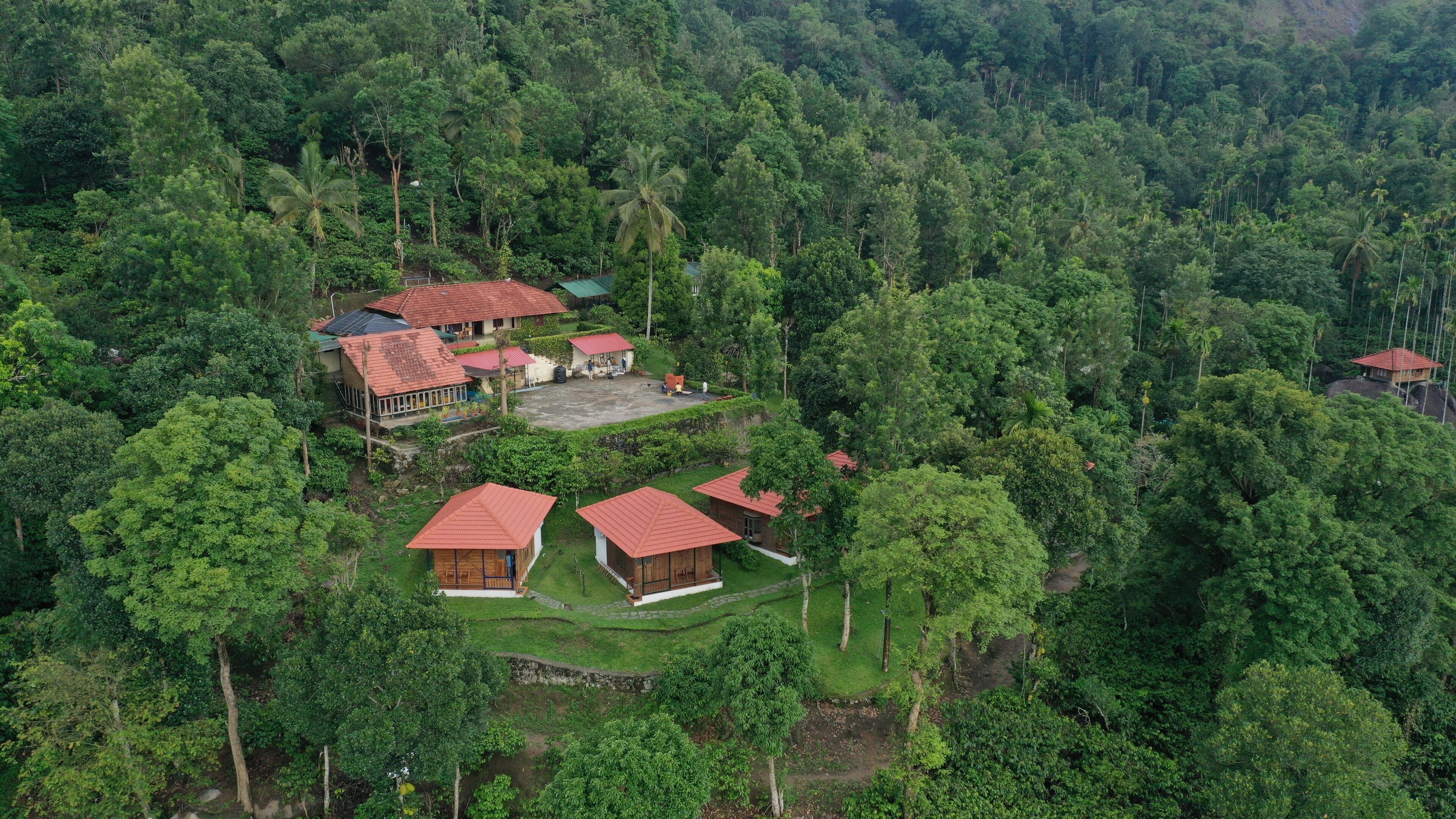 An aerial view of a resort with multiple buildings surrounded by dense forest.