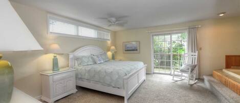 A bedroom with a bed, nightstands, a chair, a window, and a view of greenery.