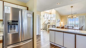 A modern kitchen with stainless steel appliances, a built-in water dispenser, and a spacious island with seating. - Waters, Ships Watch Community in Duck NC (Duck)