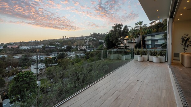 Un balcón moderno con vistas a un paisaje urbano al atardecer.