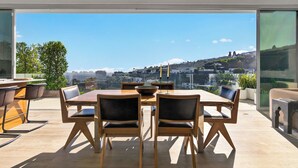 Un comedor moderno con una mesa grande y sillas, y ventanas amplias con vistas a la ciudad.