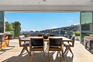 Un'area pranzo moderna con un tavolo grande e sedie, ampie finestre con vista sulla città.