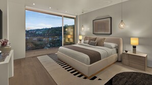 Un dormitorio moderno con una cama grande, lámparas de noche, vistas a través de una puerta de cristal y una obra enmarcada en la pared.