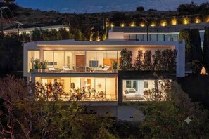 Una casa moderna a due piani con un balcone, ampie finestre e interni luminosi.
