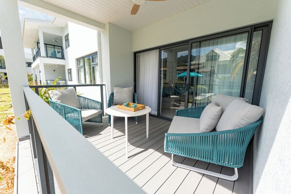 A balcony with a white sofa, a small table, and a chair.
