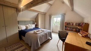 Ein Schlafzimmer mit Bett, Nachttisch, Sessel und Bücherregal.