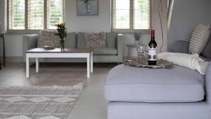 Ein modernes Wohnzimmer mit einem grauen Sofa, einem Couchtisch und einer Weinflasche auf einem Tablett.