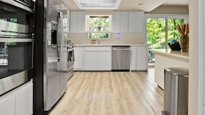 Una cucina moderna con elettrodomestici in acciaio inox, mobili bianchi e un lucernario.