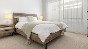 A neatly arranged bedroom with a wooden bed, white bedding, and two bedside tables with lamps. - Ultimate luxury on the canal (Geographe)