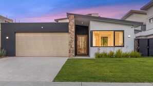 A modern two-story house with a garage, a stone pillar, and a well-maintained lawn. - Ultimate luxury on the canal (Geographe)